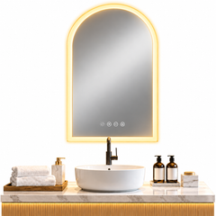 Arched LED bathroom mirror with a warm glowing edge above a vessel sink, towels and soap bottles on a marble vanity