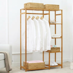 Bamboo open wardrobe clothes rack with white shirts on hangers, rattan baskets and folded towels on the shelves