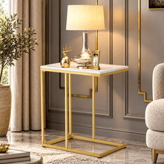 White marble look side table with a gold frame holding a table lamp, a gold deer ornament and a photo frame in a lounge