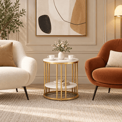 Small round gold frame side table with white tops between a cream armchair and a rust armchair holding two cups and flowers