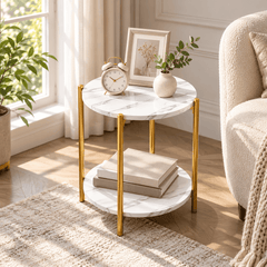 Round gold leg side table with marble look tops holding an alarm clock, a framed print and a vase, with books below