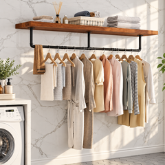 Black industrial pipe clothes rail mounted under a wooden shelf in a laundry room with clothes and towels on hangers
