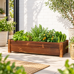Rectangular wooden planter box filled with herbs, lettuce and cherry tomatoes on a sunny patio by a white brick wall